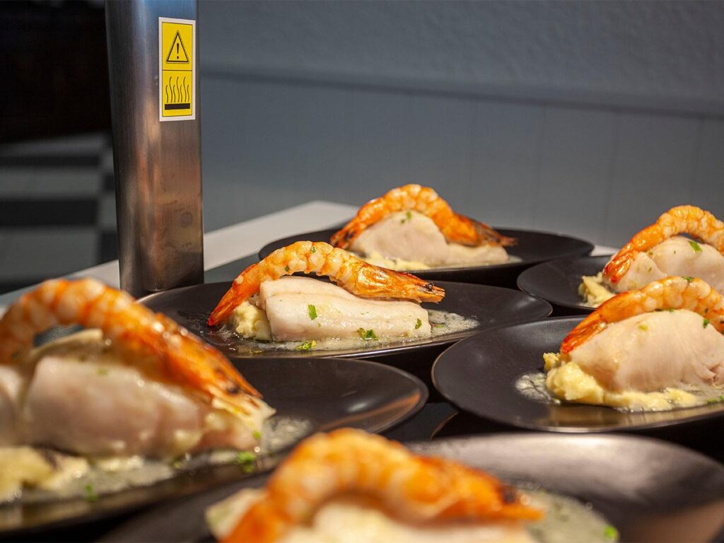 platos con merluza en salsa y un langostino encima