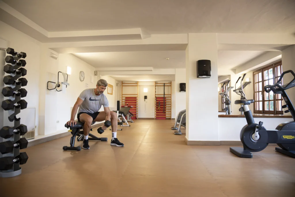 Hombre de mediana edad, haciendo biceps en un banco del gimnasio