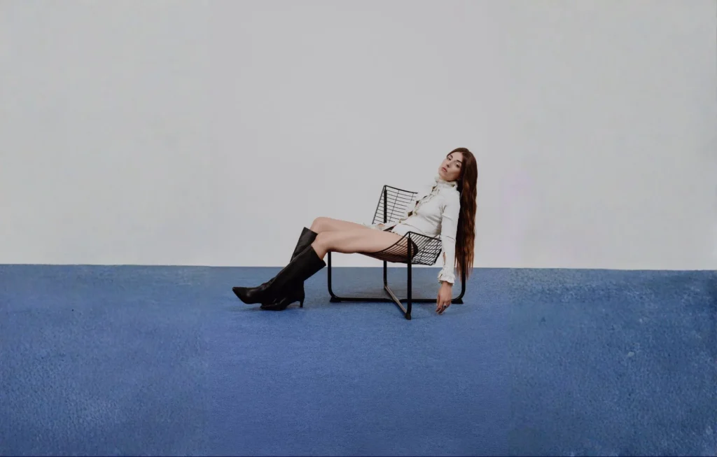 Chica Sobresalto medio sentada medio tumbada en un silla de lateral.