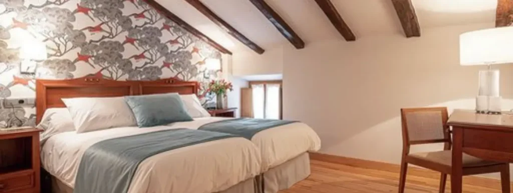 habitación abuardillada, con dos camas king independientes, con mantas de color a juego con la pared