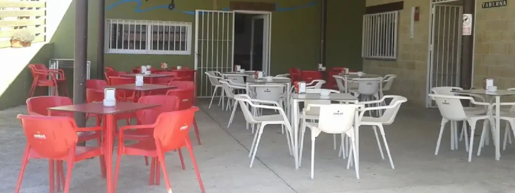 terraza del camping, con mesas y sillas de plástico.