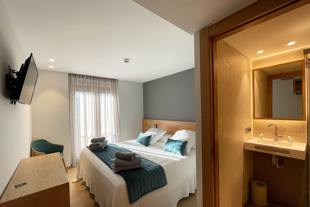 Habitación doble, con una cama de matrimonio y parte del baño