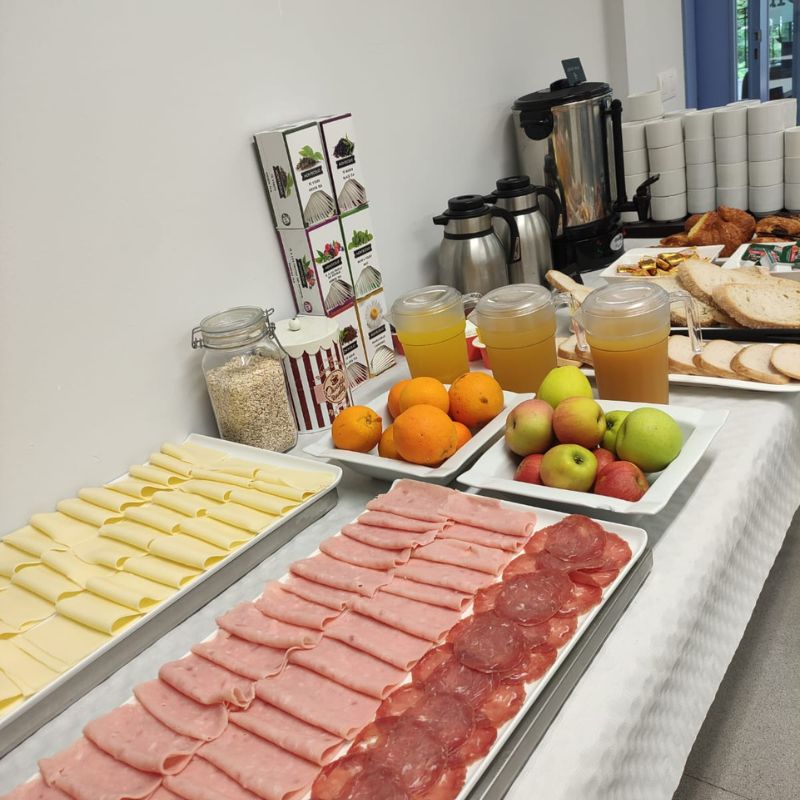 una mesa con el desayuno, queso, jamon cocido, fruta , infusiones, zumo, pan...