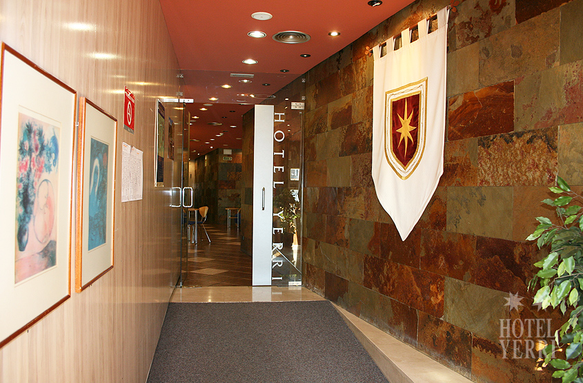 Entrada al hotel, con estandarte de una bandera y puerta acristalada