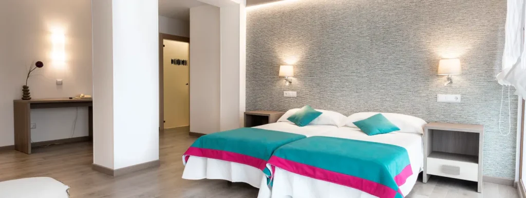 habitación con dos camas individuales y colchas de colores llamativos