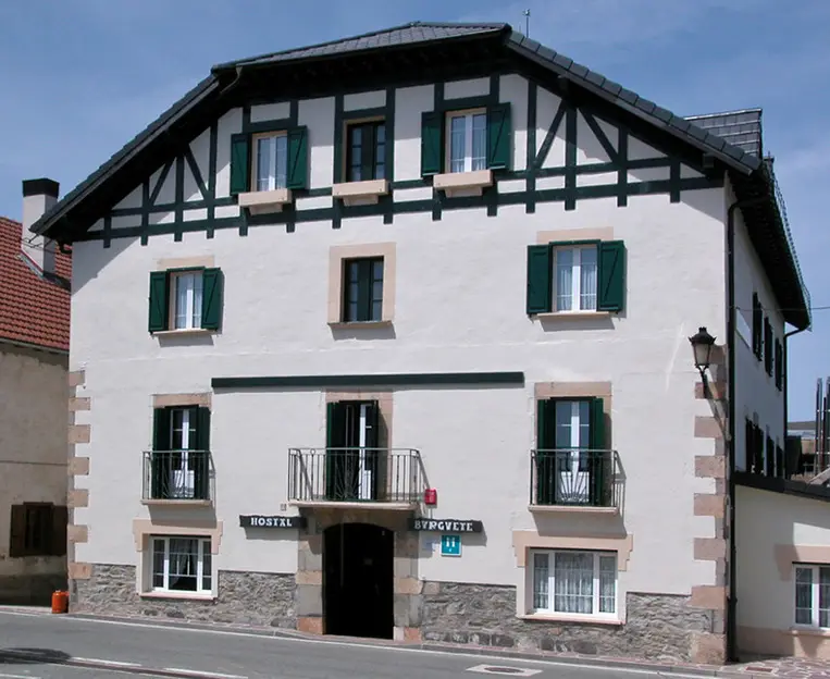 Edificio tipico del norte de navarra, casa blaca con portones de madera en ventanas y tejado empinado