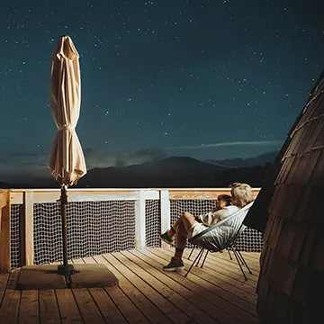 Terraza del Iglú por la noche, con un cielo estrellado. Se ve a una mujer sentada en una silla cargando a un niño