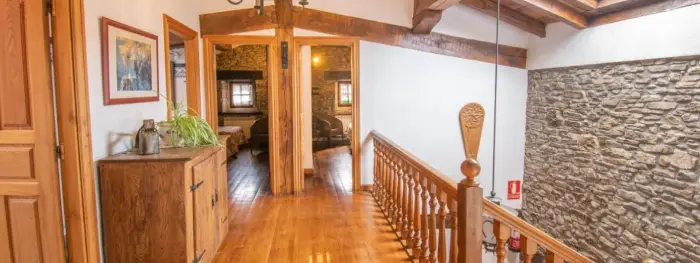 Parte superior de la casa, en la que se ven la entrada a diferentes habitaciones. Suelo de parqué y barandillas de madera. Techo aburdillado. No es accesible a movilidad reducida