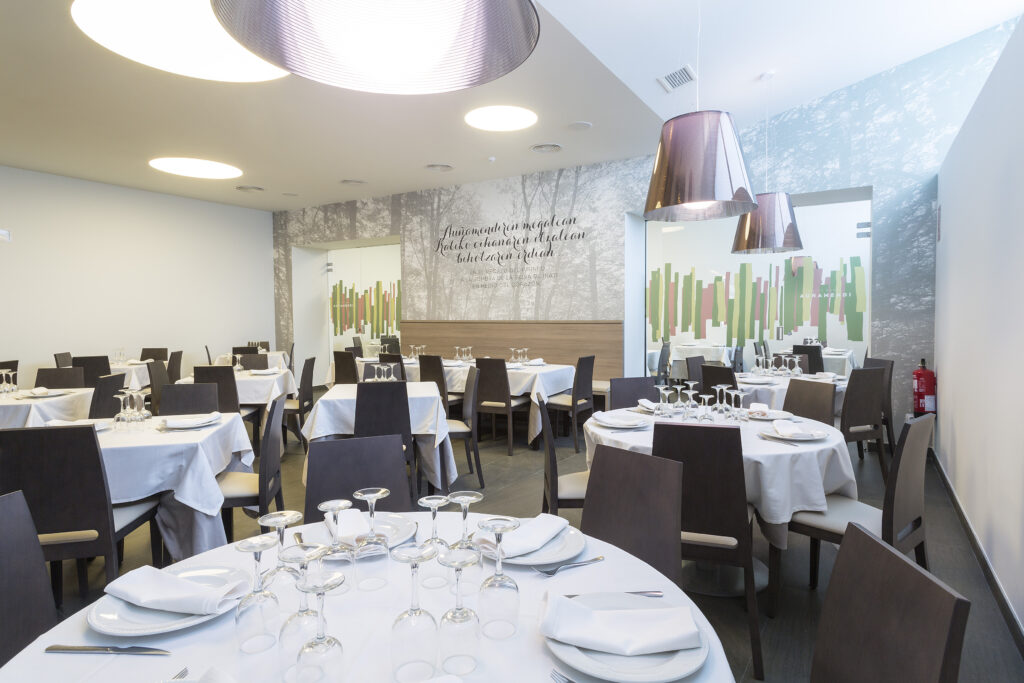 Salon comedor con mesas circulares, con montaje de platos y copas.