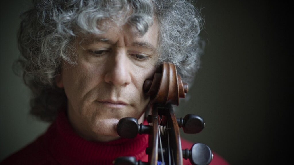 Steven Isserlis posa con el violonchelo apoyado en su pómulo y la mirada hacia abajo.