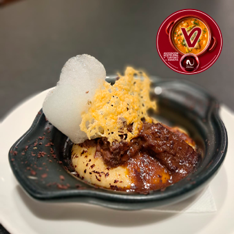Rabo estofado al estilo tradicional en su salsa sobre una crema de garbanzos de Mendogrria, infusionada con tomillo, con un toque de chocolate amargo rallado, teja de queso idiazábal, aire de romero y pétalos de flor de sechuan.