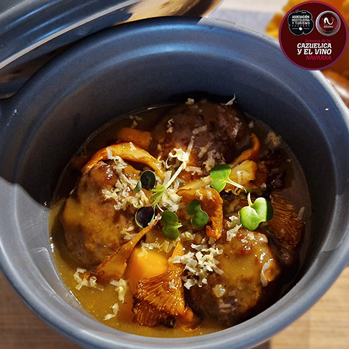 albóndigas de jabalí guisadas en un fondo oscuro elaborado con huesos de jabalí tostados y verduras como base. La cazuela integra también calabaza ecológica asada, setas de temporada y una tierra de castaña asada.