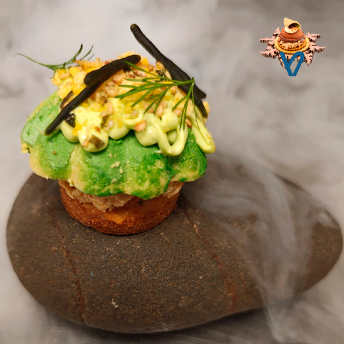 Reinterpretación marina y creativa del clásico txangurro a la donostiarra; base de pan frito, pate de coral de txangurro , ensaladilla de txangurro estilo thai, huevas de tobiko, sriracha verde, cascara comestible con mayonesa de lima kaffir y albahaca.