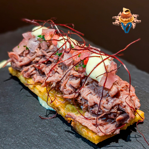 Tostada de plátano macho frito, jugosa carne de ternera marinada con café, xnipec de piña e hibisco, mayonesa de lima y un toque de ito togarashi.