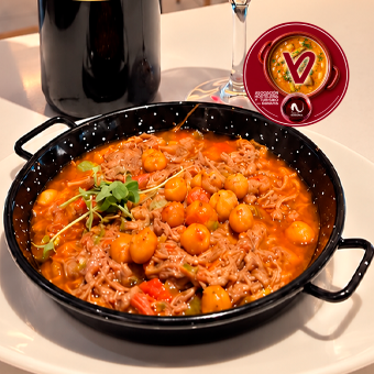 Cazuelica de ternera de Navarra cocida y deshilachada, incorporada a un sofrito de cebolla, pimiento verde, pimiento rojo, ajo y tomate. Se acompaña de garbanzos fritos y se termina con el caldo de la cocción de la carne, que aporta intensidad y sabor al conjunto.