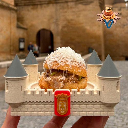 Pan chino aireado relleno de un guiso de cordero Navarro y piñones, alioli de ajo negro, chips de alcachofa, polvo de shitake y nube de queso Idiazabal.