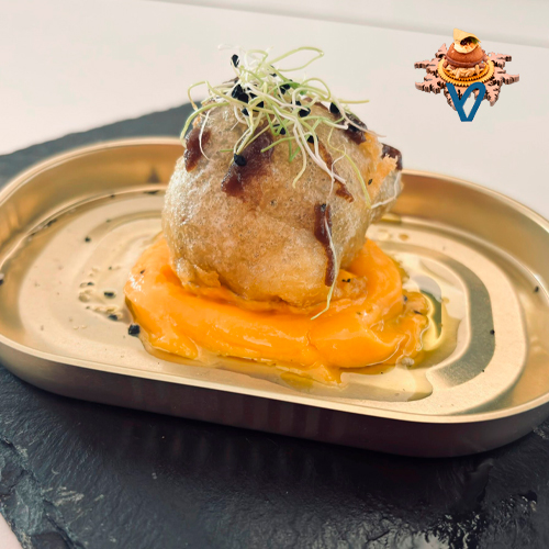 Corazón de alcachofa rellena de guiso carrillera ibérica, pasada por pasta orly sobre una parmentier de capote con toque de mango, finalizando con un decirlas del propio guiso de las carrilleras y brotes de alfalfa.