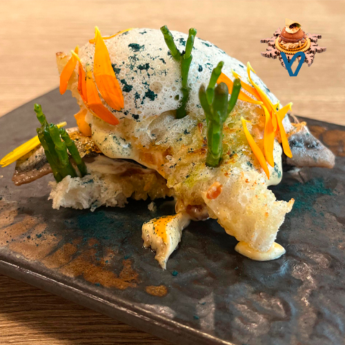 Es un mini bocadillo de anchoa fresca marinada acompaña de un salmorejo y de una mayonesa ahumada y un aire de ajo blanco.