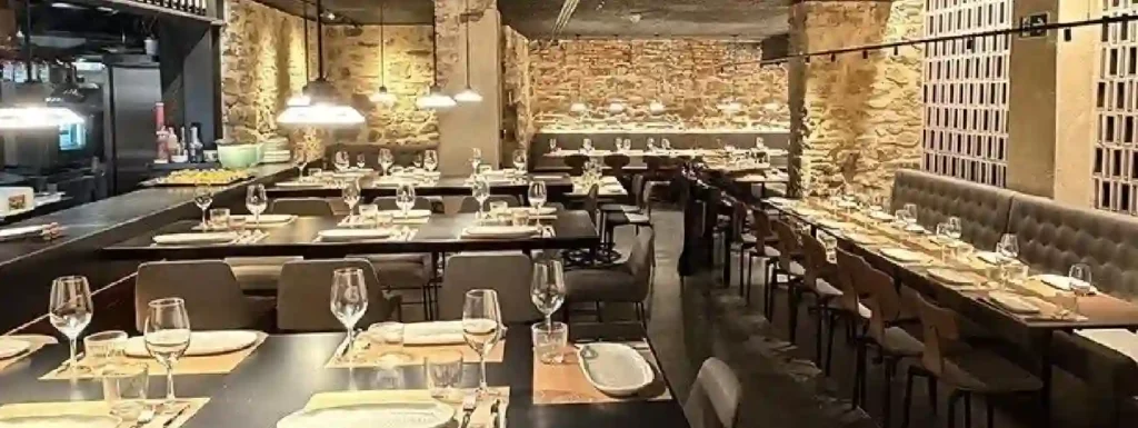 interior del restaurante, paredes de piedra, con mesas de color oscuro.