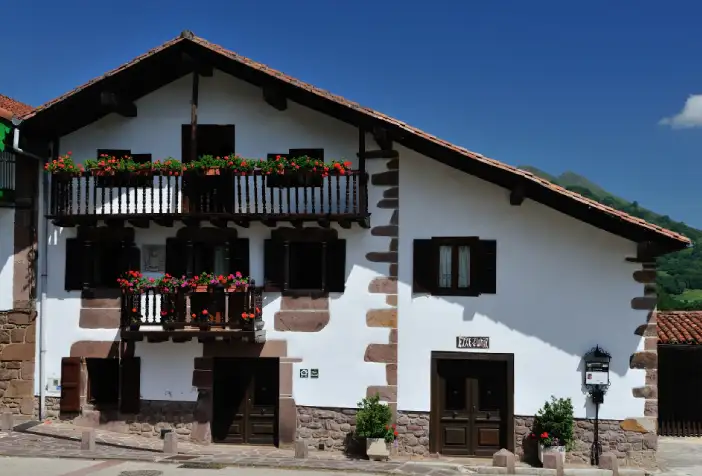 Casa de Pueblo de la zona de Baztan, piedra pintada de blanco con ventanas y balconada en madera
