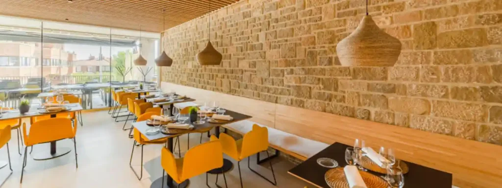Salon de comedor, con paredes de piedra y detalles en naranja