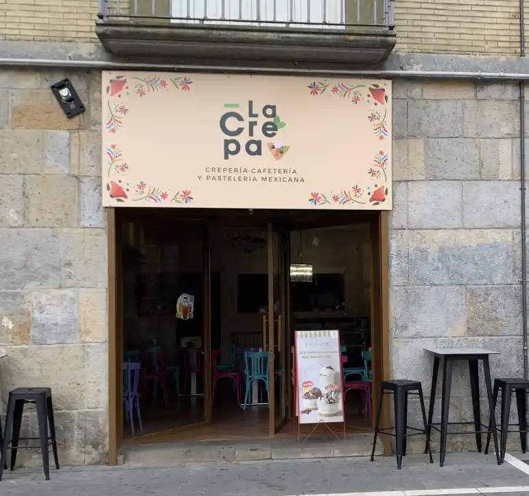 cartel floral en tonos pastel con el nombre del establecimiento, porton de madera con gran cristalera