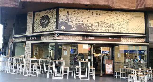 Amplia fachada en esquina, con mesas y taburetes altos
