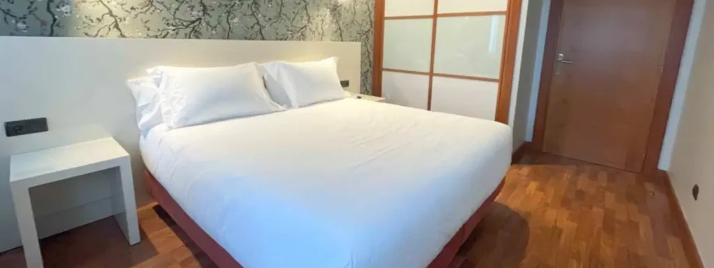 Habitación con una mesilla al lateral de la cama de matrimonio