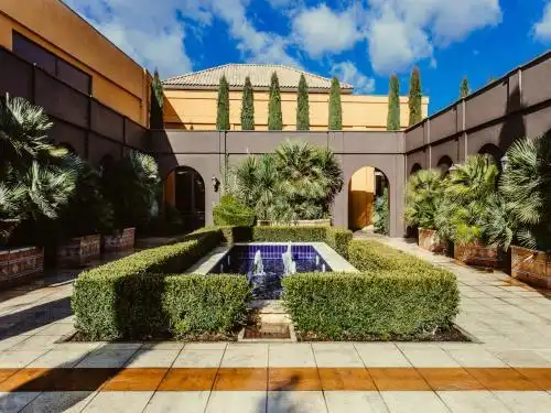 Terraza interior del hotel, estilo arave, con plantas al rededor de una fuente central