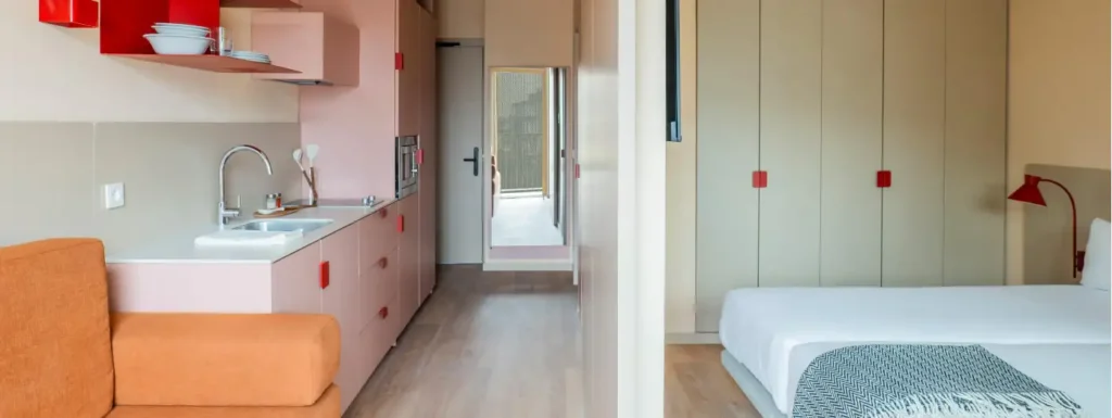 apartamento en tonos rosas, cocina americana a la izquierda y dos camas individuales a la derecha
