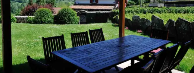 Terraza con sombra y mesa alargada en el fondo el jardin