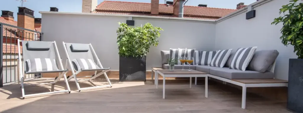 Terraza en solarium, con hamacas en formato silla y un sillon en L con cojines de rayas. Una mesa baja con dos zumos encima.