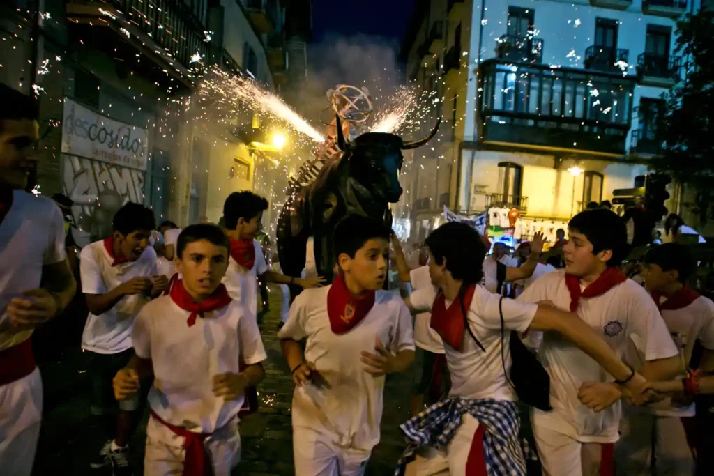 Niños corren delante del Toro de Fuego durante las fiestas de San Fermín
