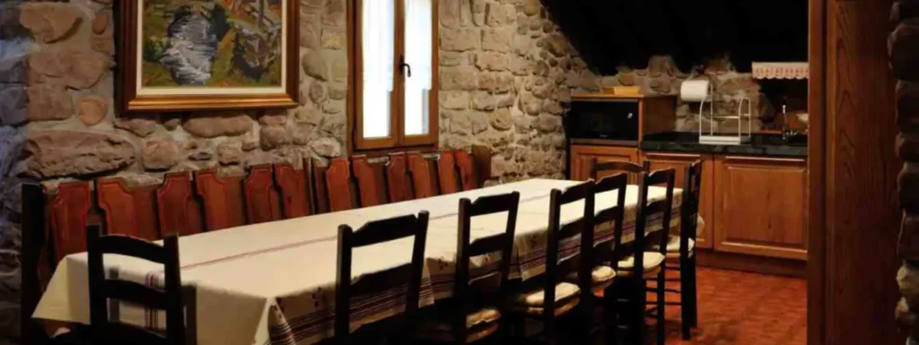 Mesa para 12 comensales, con sillas d emadera oscura, y paredes de piedra