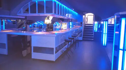 Barra del establecimiento, con taburetes altos y una luz azulada