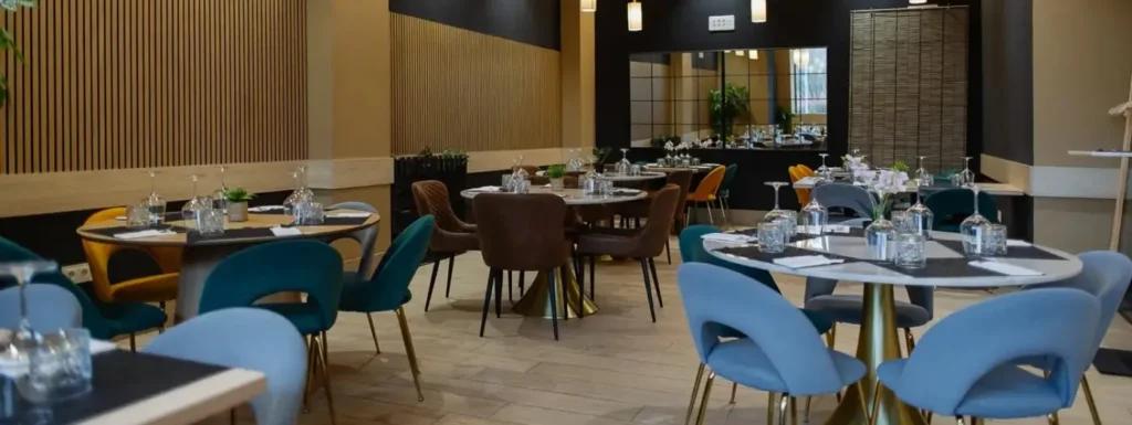 Interior del restaurante, con mesas circulares y sillas azules a su al rededor