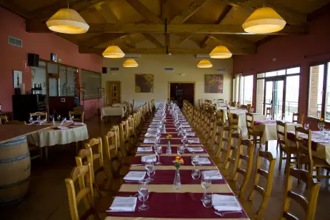 Comedor del restaurante cn mesas y sillas de madera y manteleria roja