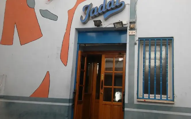 Acceso al pub, fachada blanca con motivos naranjas y letras azules