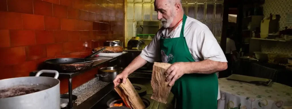 Cocinero preparando fuego de leña, con delantal verde