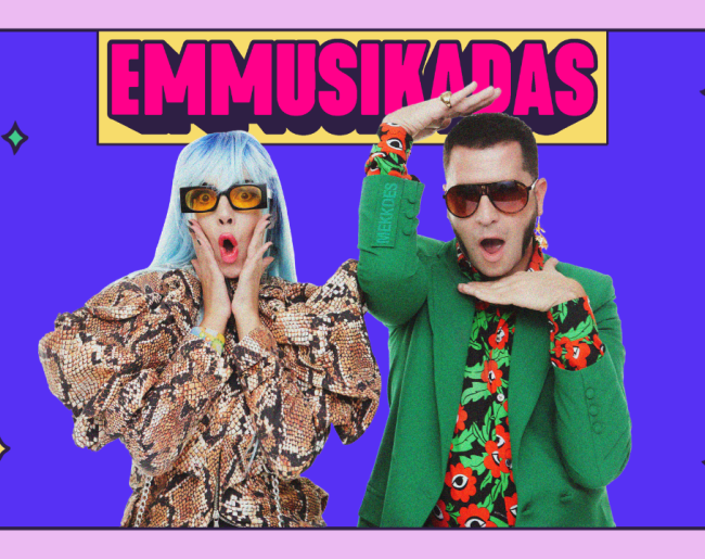 Cartel colorido de Emmusikadas, con fondo morado y dos artistas en primer plano con gafas de sol y vestuario llamativo, posando con gestos expresivos y tono desenfadado.