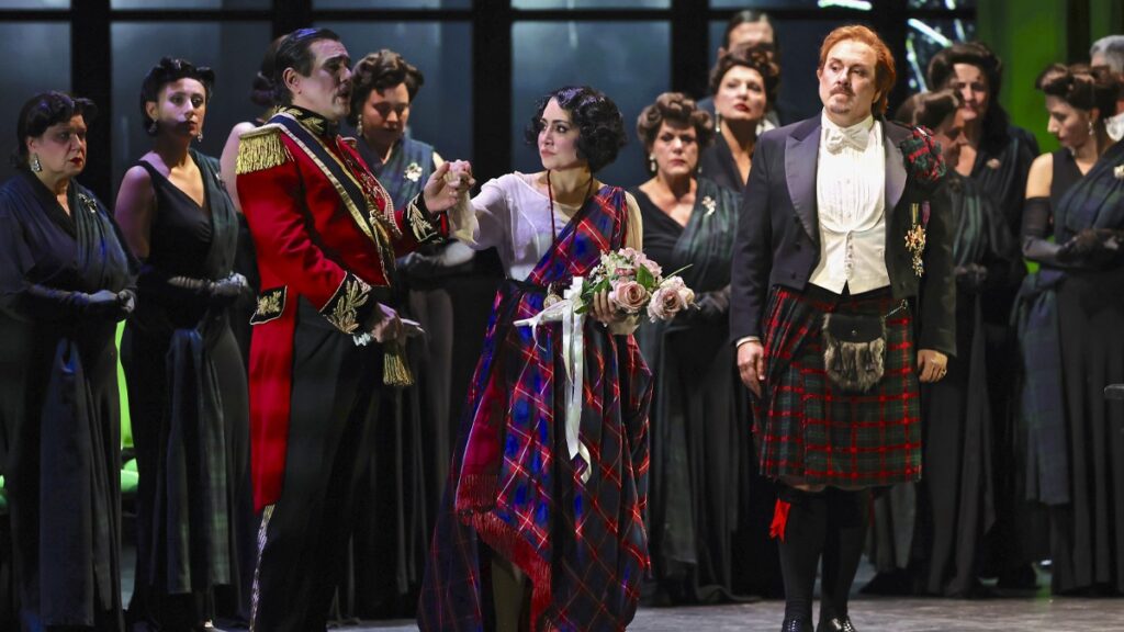 cantander en una escena d ela obra, en primera línea una pareja agarrados de la mano, él con traje militar