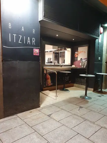 Entrada del establecimiento, con una pequeña terraza cubierta y mesas altas