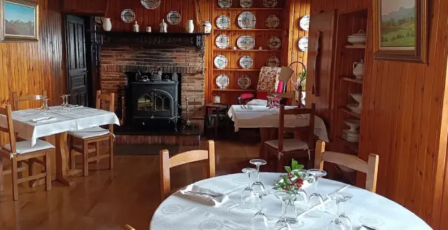 Salon cubierto de madera, con una chimenea de fondo y mesas para los comensales