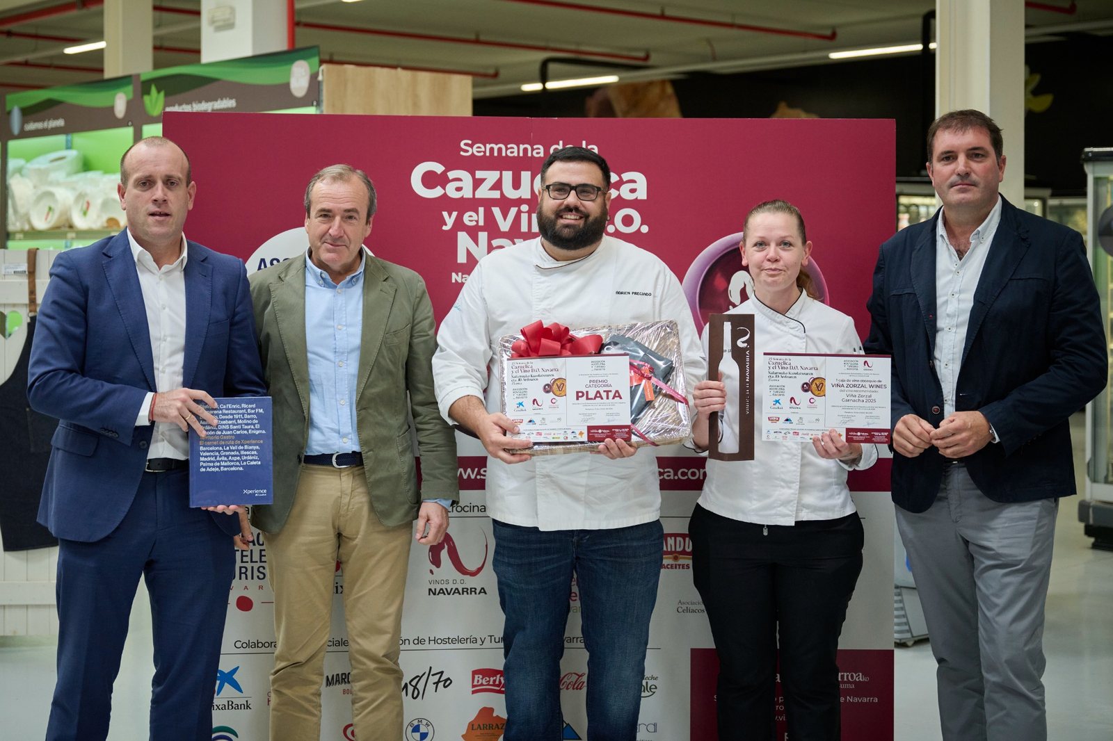 Entrega del Premio Plata de la 25ª Semana de la Cazuelica y el Vino D.O. Navarra, con el equipo premiado mostrando el diploma, la escultura y los obsequios recibidos.